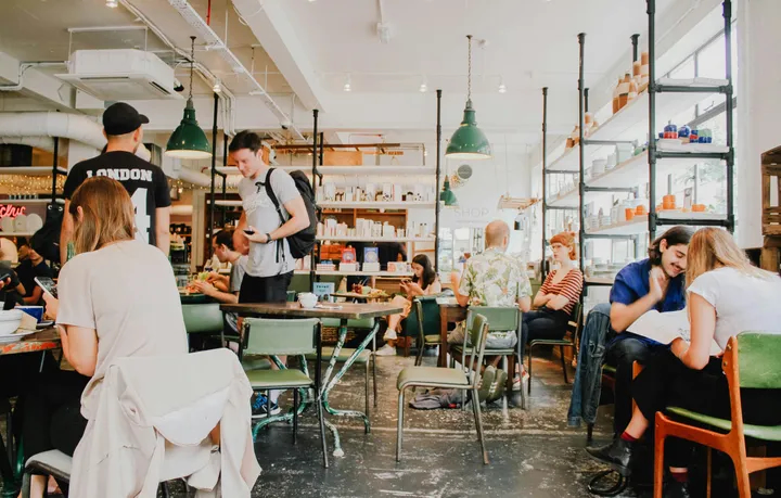 Salle de café restaurant animée avec clients attablés et sol béton