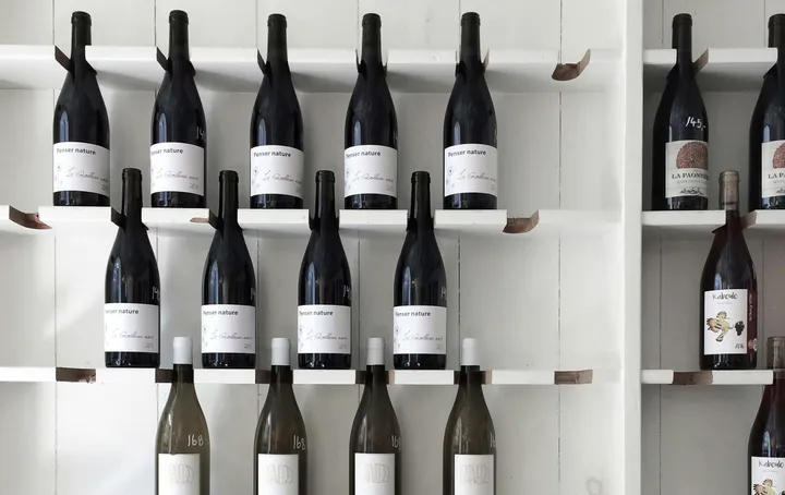 Étagères minimalistes avec des bouteilles de vin exposées dans un espace épuré. La présentation met en avant des vins rouges et blancs dans un décor moderne et lumineux, soulignant l'élégance et la simplicité d'une cave ou boutique spécialisée.
